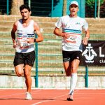 Two male marathon runners competing in a track race during a sunny day in Lisbon.